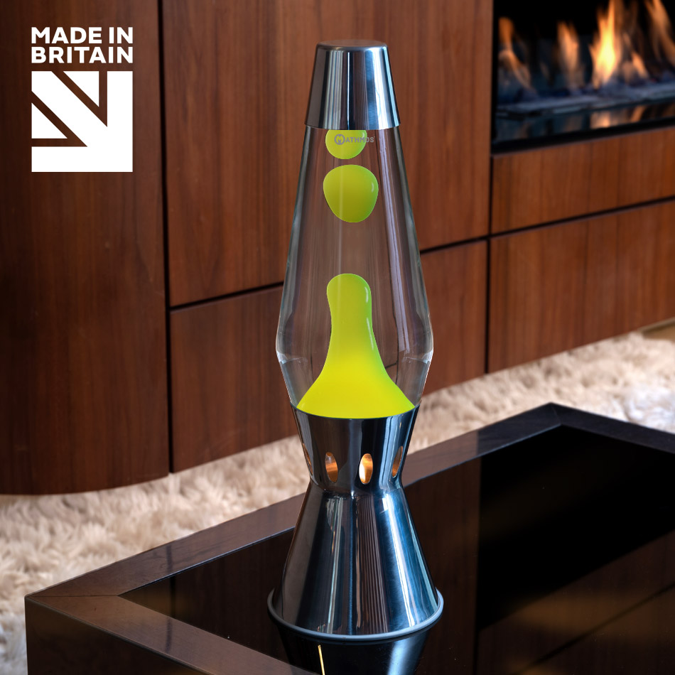 Lampe à lave à bougie Mathmos Astro Flame en argent avec liquide transparent et lave jaune sur une table noire, avec une cheminée en arrière-plan