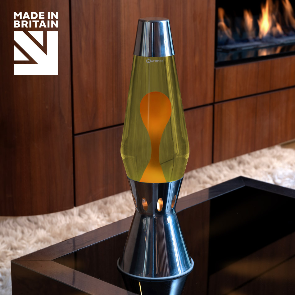 Lampe à lave à bougie Mathmos Astro Flame en argent avec liquide jaune et lave orange sur une table noire, avec une cheminée en arrière-plan