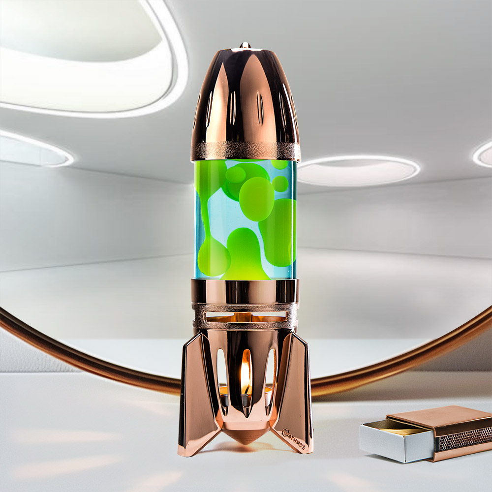 Lampe à lave à bougie en cuivre en forme de fusée Mathmos Fireflow avec liquide bleu et lave jaune sur fond clair avec une boîte d'allumettes