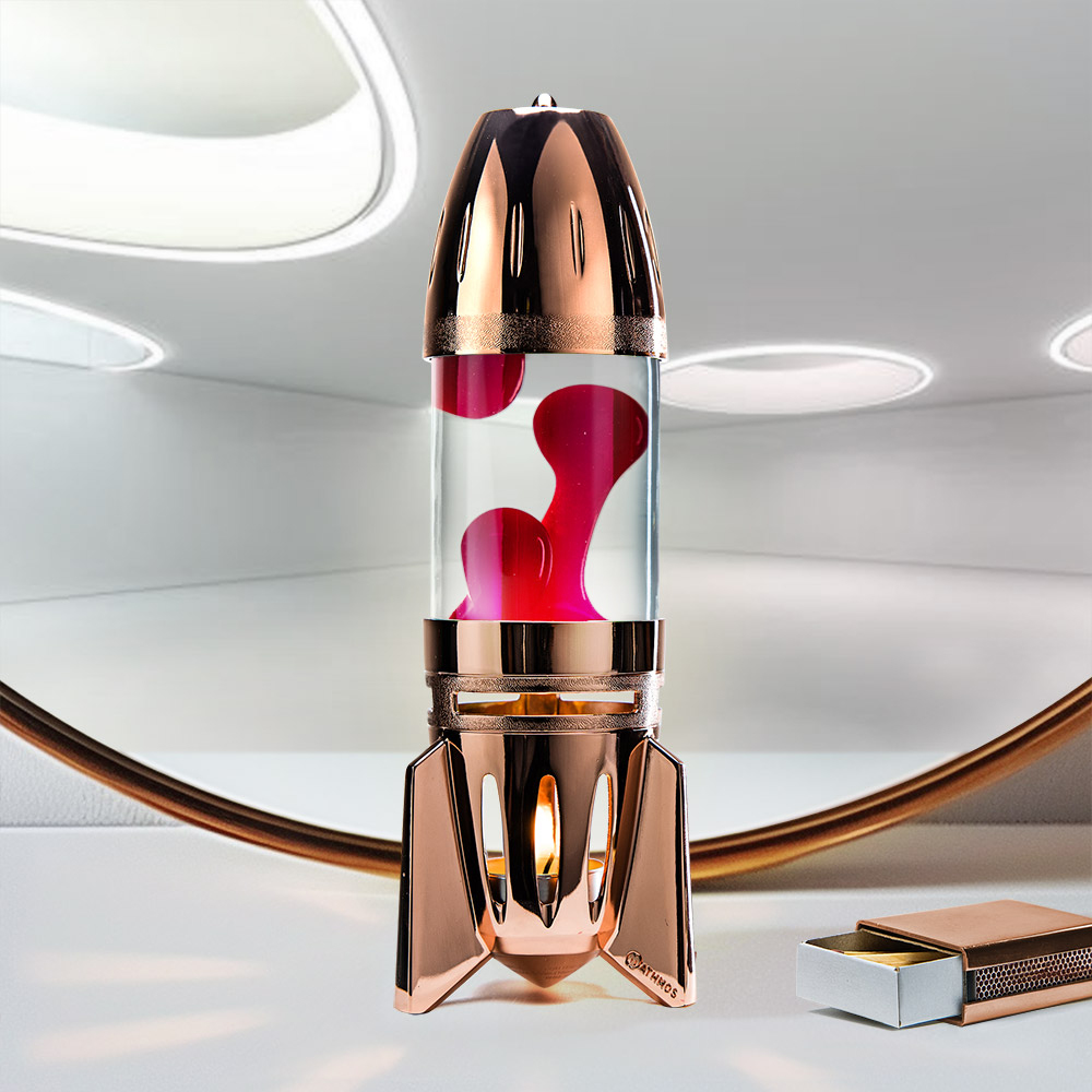 Lampe à lave à bougie en cuivre en forme de fusée Mathmos Fireflow avec liquide transparent et lave rouge sur fond clair avec une boîte d'allumettes