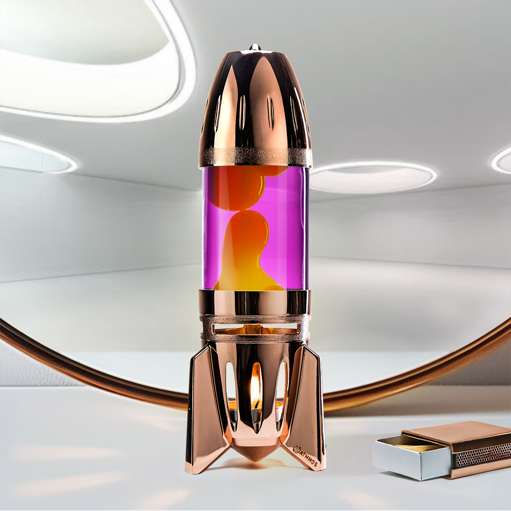Lampe à lave à bougie en cuivre en forme de fusée Mathmos Fireflow avec liquide rose et lave jaune sur fond clair avec une boîte d'allumettes