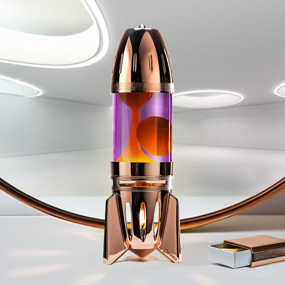 Lampe à lave à bougie en cuivre en forme de fusée Mathmos Fireflow avec liquide violet et lave orange sur fond clair avec une boîte d'allumettes
