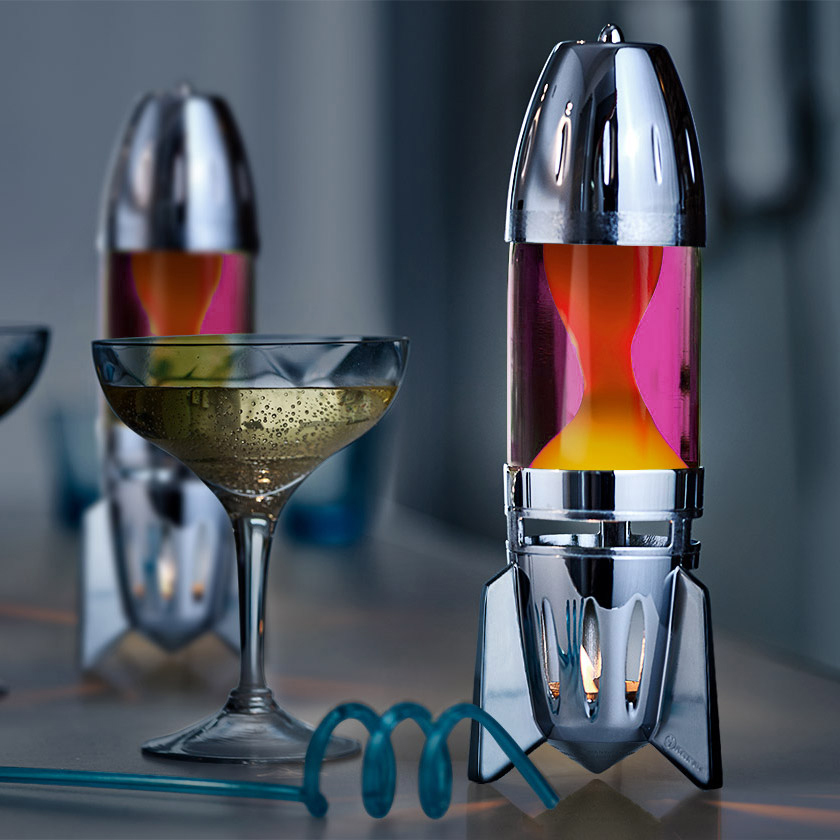 Lampe à lave à bougie Mathmos Fireflow avec corps argenté, liquide rose et lave jaune, détail d'intérieur moderne sur une table