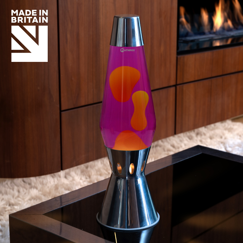 Lampe à lave argentée « Mathmos Astro Flame » avec liquide rose et cire jaune sur une table basse noire.