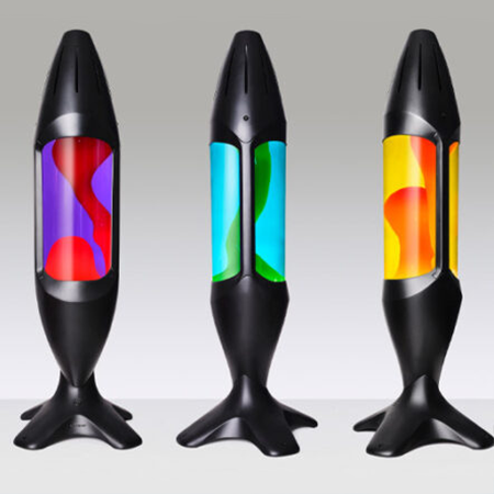 Trois lampes à lave noires Mathmos iO avec différentes couleurs de liquide et de lave sur un fond clair.